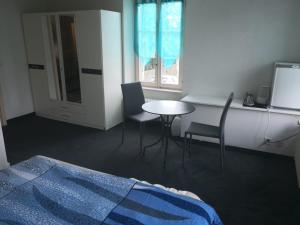 a bedroom with a table and chairs and a bed at Hôtel- restaurant Le Bras d'Or in Mathod
