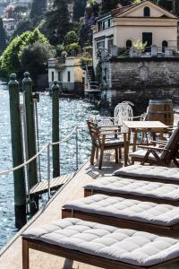 a dock with chairs and tables on the water at Darsena di Riva Grande in Moltrasio