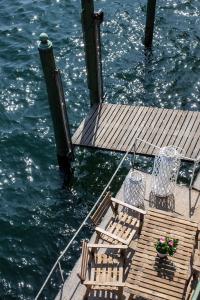 a wooden pier with chairs and the water at Darsena di Riva Grande in Moltrasio