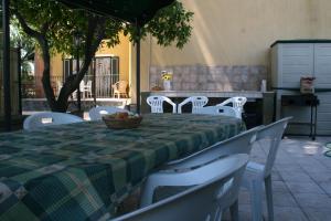 einen Tisch mit weißen Stühlen und einem grünen und weißen Tischtuch in der Unterkunft B&B Etna Country in Tremestieri Etneo