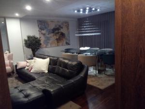 a living room with a black leather couch and a table at Luxury 3 Bedroom Penthouse With Private Garage in Braga