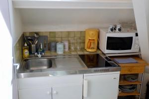a kitchen with a sink and a microwave at Studio Confort, en face du campus 1 et du tramway in Caen +4 photos