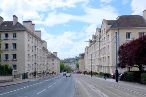 a city street with buildings and cars on the road at Studio Confort, en face du campus 1 et du tramway in Caen