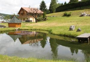 une maison assise à côté d'un étang avec un banc dans l'établissement Chalet centaurée - Rémy HEROLD, à Xonrupt-Longemer