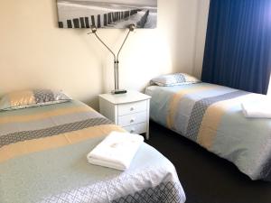 a bedroom with two beds and a lamp on a night stand at Middleton Bay Retreat in Albany
