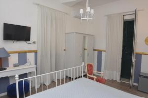 a bedroom with a bed and a desk and a tv at Brenta 12 in Messina