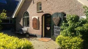 a brick house with a door with a sign on it at Bed and Breakfast Klein Groenbergen in Leersum