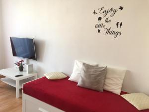 um quarto com uma cama com lençóis vermelhos e uma televisão em Apartment Lilly Olomouc em Olomouc