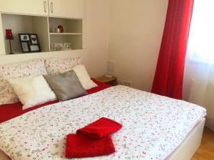 Apartment Lilly Olomouc في أولوموك: غرفة نوم مع سرير وفوط حمراء عليه