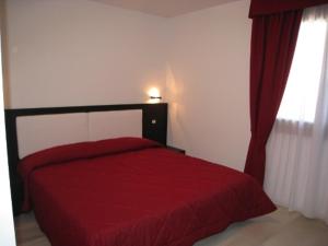 ein rotes Bett in einem Zimmer mit Fenster in der Unterkunft Sillia Appartamenti in Pinzolo