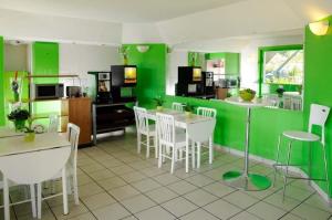 a kitchen with green walls and white tables and chairs at Lemon Hotel in Le Coteau