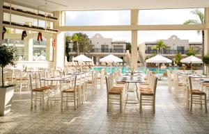 a restaurant with tables and chairs and a swimming pool at Louis Paphos Breeze in Paphos City