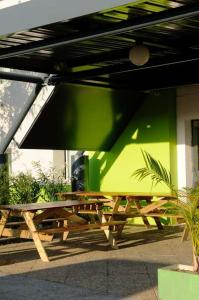a wooden picnic table in front of a green wall at Lemon Hotel in Le Coteau