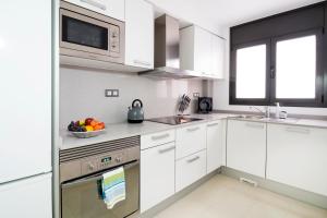 a white kitchen with a bowl of fruit on the counter at Heart of Sitges in Sitges