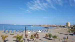 a beach with chairs and umbrellas and the ocean at Torres del Sol Playa de Las Vistas FREE WIFI in Playa de las Americas