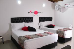 2 bedden in een kamer met witte muren en rode kussens bij Hotel Palma Rosa Medellin in Medellín