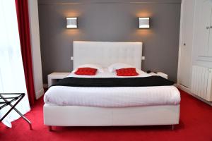 a bedroom with a large white bed with two red pillows at Hôtel Le Square in Aurillac