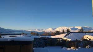 uma casa coberta de neve com montanhas ao fundo em Tekapo Heights em Lake Tekapo