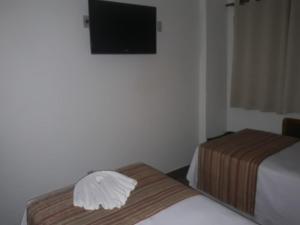 a hotel room with two beds and a flat screen tv at Mabruk Barretos Apart Hotel in Barretos