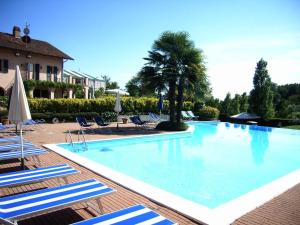 uma grande piscina com cadeiras e guarda-sóis em Hostellerie Du Golf em Pecetto