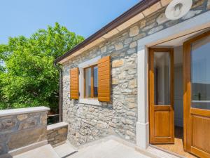 ein Steinhaus mit Holztüren und Fenstern in der Unterkunft VillaNuova in Šušnjevica