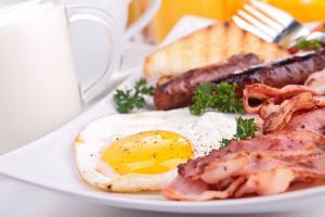 a plate of breakfast food with a fried egg and bacon at The Manor Elstree in Elstree