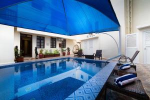 ein Schwimmbad mit einem großen blauen Regenschirm darüber in der Unterkunft Spice Palace Hotel in Zanzibar City