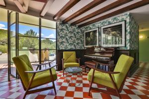 a living room with green chairs and a grand piano at Cubanito Ibiza in San Antonio