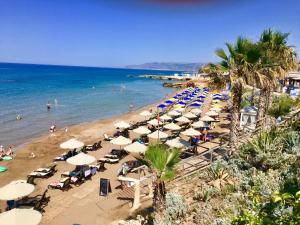 a beach with umbrellas and people on the water at Rossi apartment in Hersonissos