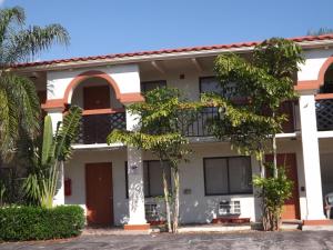 a white building with trees in front of it at Lake Side Lodge in Lake Worth