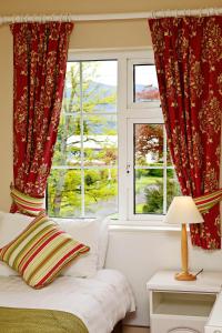 a bedroom with red curtains and a bed and a window at Ashville House in Killarney