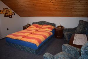 1 cama con almohadas de color naranja en una habitación con 2 sillas en Zsuzsi Apartman, en Zalakaros