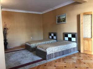 two beds in a room with wooden floors at Guest House kartvelishvili in Batumi
