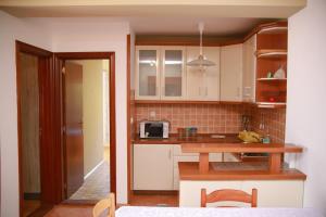 een keuken met witte kasten, een tafel en een magnetron bij Ana in Budva
