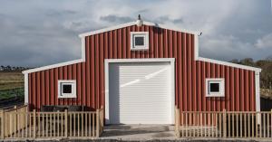 un edificio rojo y blanco con garaje en The Wild Atlantic Way Barn, en Oranmore