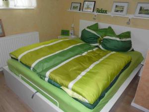 a large bed with green sheets and pillows at Ferienwohnung Winter in Lutherstadt Wittenberg