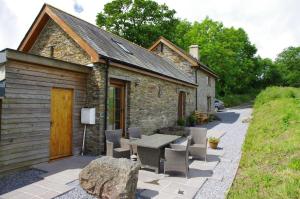 - un bâtiment en pierre avec une table et des chaises devant dans l'établissement Jacks Cottage, à Totnes