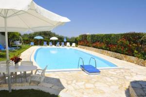 a swimming pool with a table and an umbrella at Irene Apartments in Acharavi