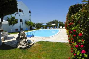 a swimming pool next to a building with flowers at Irene Apartments in Acharavi +17 photos