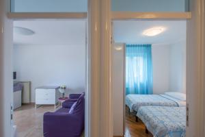 a bedroom with two beds and a purple couch at Apartments Bella Vista in Umag