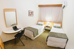 クリチバにあるHotel Aladdinのベッド2台と鏡が備わるホテルルームです。