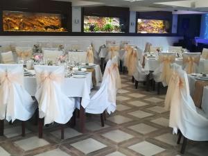 uma sala de jantar com mesas brancas e cadeiras com arcos em Hotel Elizabeth em Baja