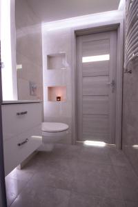 a white bathroom with a toilet and a door at Szafir in Kuźnica