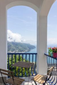 balcón con mesa, sillas y vistas al océano en Angiem Holiday House Ravello, en Ravello