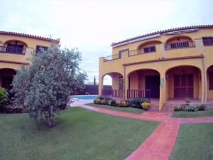 レスカラにあるVACAY Apartamento Tropicanaの庭とプール付きの大きな黄色の家