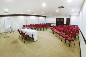 een vergaderzaal met rode stoelen en een witte tafel bij Hotel Aladdin in Curitiba