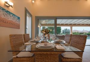 a dining room with a glass table and chairs at Villa Emerald in Porto Heli