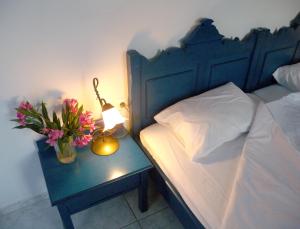 a bed with a table with a lamp and flowers on it at Theophili in Zefiría