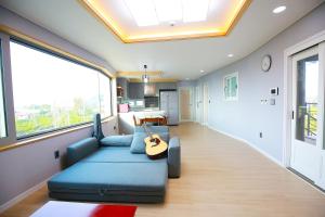 a living room with a blue couch and a guitar at Seong Ge Dol Pension in Seogwipo