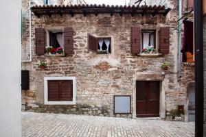 un antiguo edificio de ladrillo con ventanas y flores. en Apartman Tereza, en Rovinj